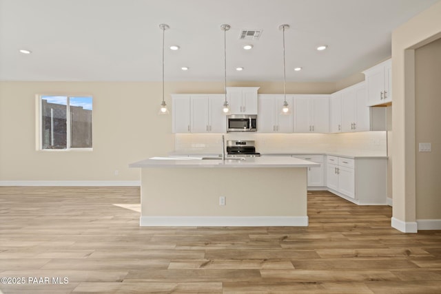 kitchen featuring pendant lighting, white cabinetry, and stainless steel appliances