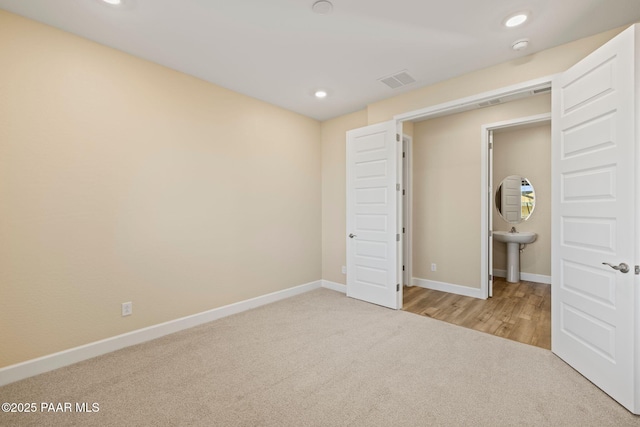 unfurnished bedroom featuring sink and light colored carpet