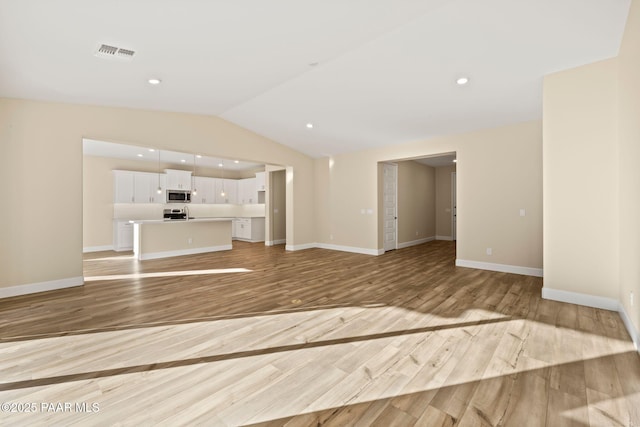 unfurnished living room featuring vaulted ceiling and light wood-type flooring