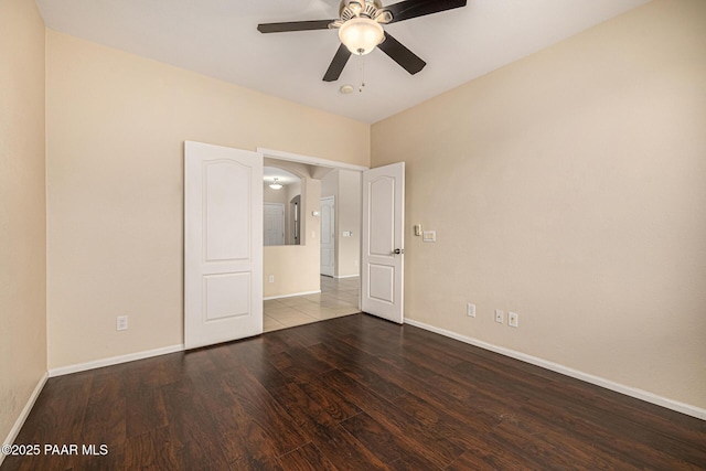 8214 S 48th Dr, Laveen, AZ 85339 - unfurnished bedroom featuring wood finished floors, arched walkways, and ceiling fan