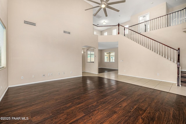 8214 S 48th Dr, Laveen, AZ 85339 - unfurnished living room featuring ceiling fan, arched walkways, wood finished floors, a high ceiling, and stairway