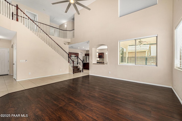 8214 S 48th Dr, Laveen, AZ 85339 - unfurnished living room featuring a ceiling fan, wood finished floors, high vaulted ceiling, stairway, and arched walkways