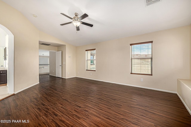 8214 S 48th Dr, Laveen, AZ 85339 - empty room with dark wood finished floors, ceiling fan, healthy amount of natural light, arched walkways, and lofted ceiling