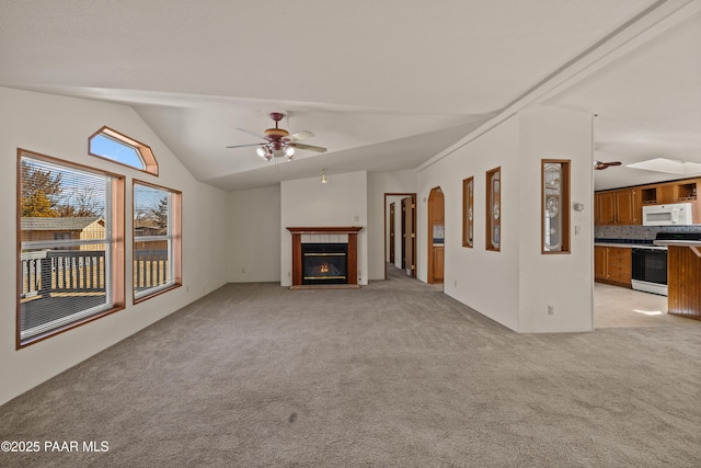 unfurnished living room with ceiling fan, light colored carpet, a fireplace, and vaulted ceiling