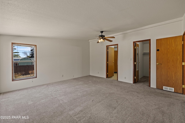 unfurnished bedroom with ceiling fan, carpet flooring, a textured ceiling, and a spacious closet