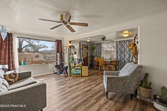 living room featuring ceiling fan, hardwood / wood-style floors, and a textured ceiling