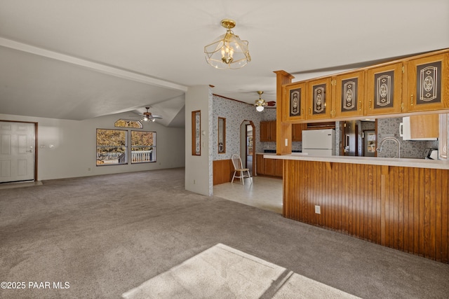 kitchen with lofted ceiling, hanging light fixtures, light carpet, kitchen peninsula, and white fridge