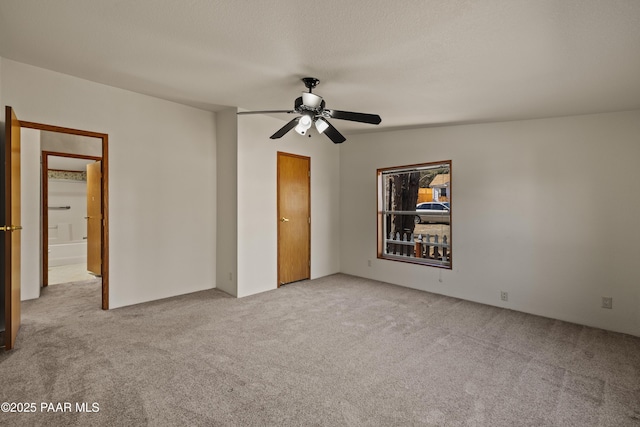 spare room featuring light carpet, a textured ceiling, and ceiling fan