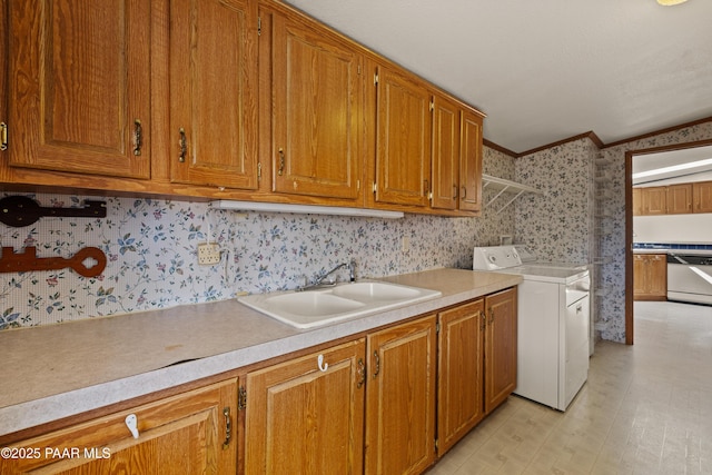 clothes washing area featuring cabinets, ornamental molding, separate washer and dryer, and sink