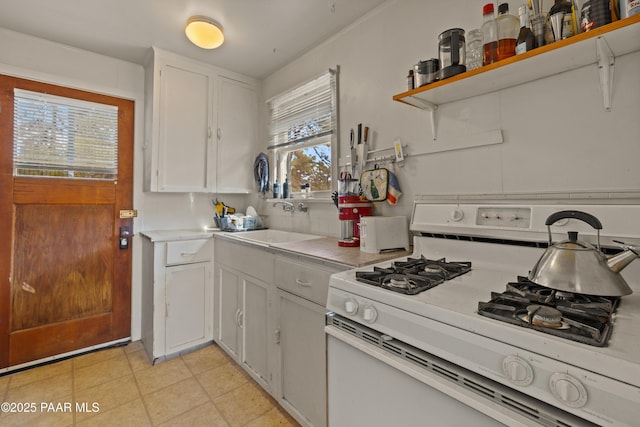 kitchen featuring white cabinetry, sink, and white gas stove