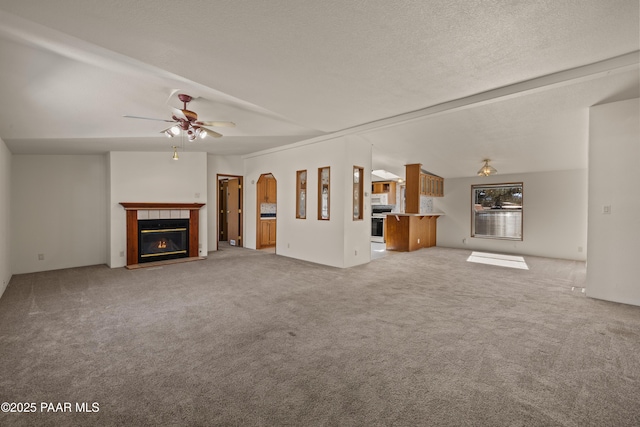 unfurnished living room featuring ceiling fan, carpet, a textured ceiling, and a fireplace