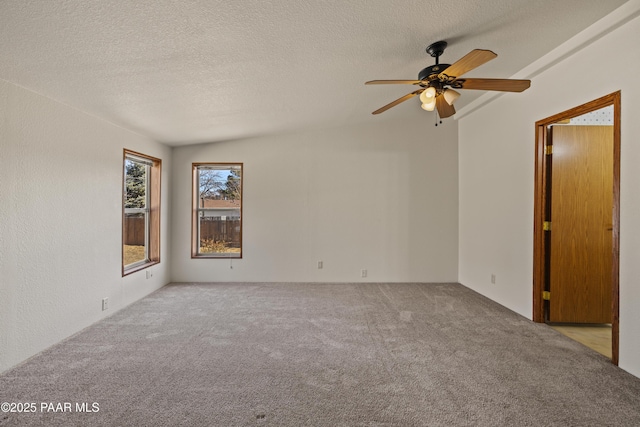 carpeted spare room featuring ceiling fan, vaulted ceiling, and a textured ceiling