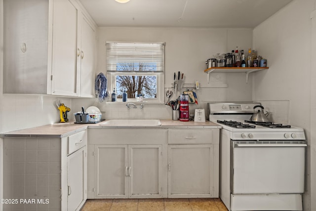 kitchen featuring white cabinetry, sink, decorative backsplash, and white gas range oven