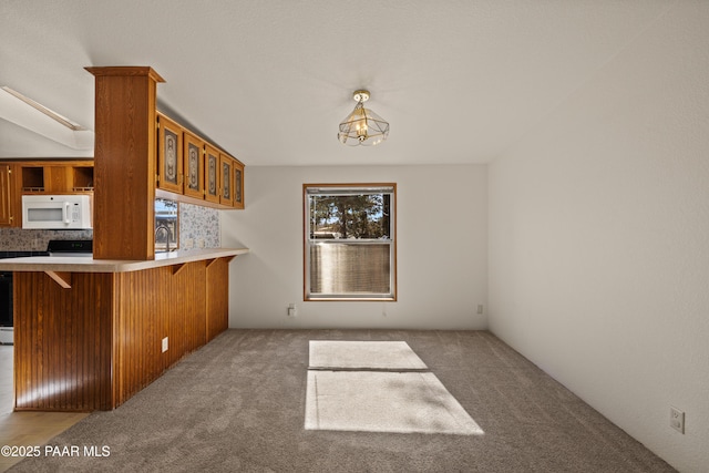 kitchen featuring pendant lighting, a kitchen bar, carpet flooring, and kitchen peninsula