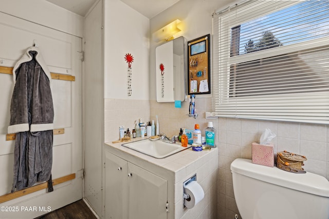 bathroom featuring vanity, toilet, and tile walls