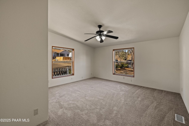 carpeted spare room with lofted ceiling, a textured ceiling, and ceiling fan