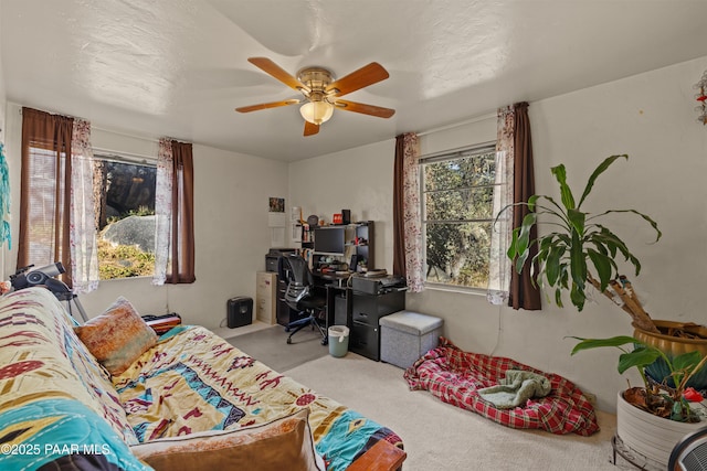 office area with light carpet, ceiling fan, and a textured ceiling