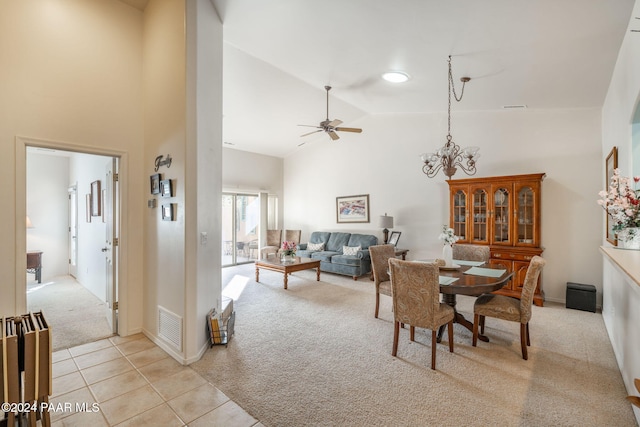 dining room featuring ceiling fan with notable chandelier, light colored carpet, and high vaulted ceiling