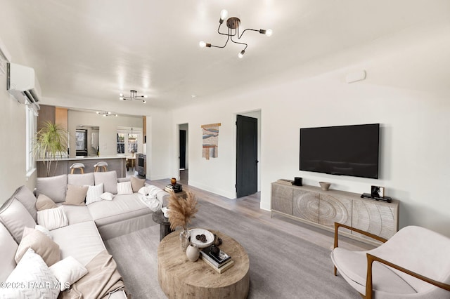 living room featuring a notable chandelier, light hardwood / wood-style floors, and an AC wall unit