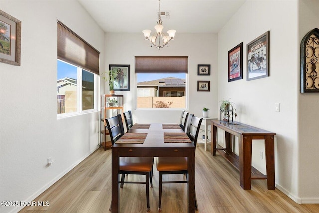 dining room featuring light wood-type flooring and an inviting chandelier