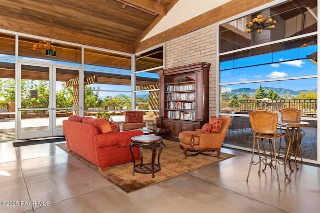 sunroom / solarium featuring a mountain view, an inviting chandelier, wood ceiling, and vaulted ceiling