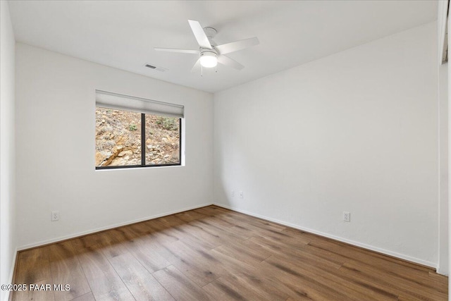 unfurnished room featuring baseboards, wood finished floors, visible vents, and ceiling fan