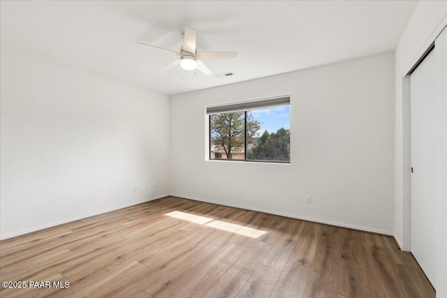 unfurnished bedroom featuring visible vents, a closet, wood finished floors, and a ceiling fan