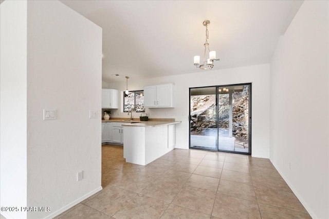 kitchen featuring a notable chandelier, decorative light fixtures, white cabinetry, a peninsula, and light countertops