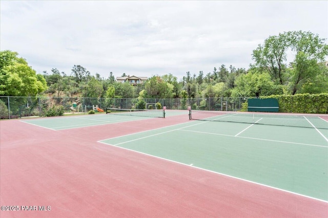 view of tennis court featuring community basketball court and fence