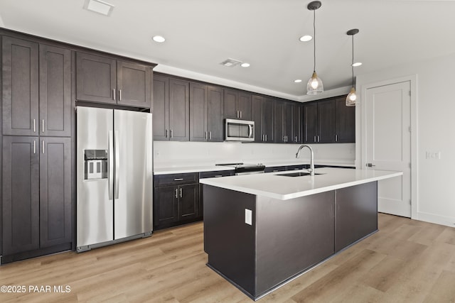 kitchen featuring light wood-type flooring, dark brown cabinets, stainless steel appliances, sink, and hanging light fixtures