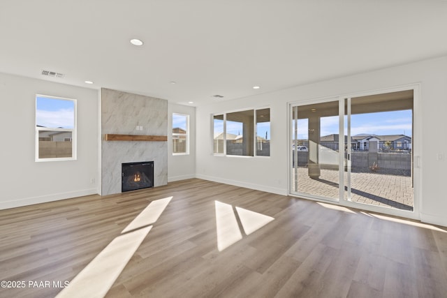 unfurnished living room featuring a large fireplace and light hardwood / wood-style flooring