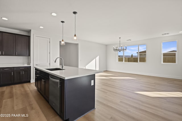 kitchen featuring a kitchen island with sink, hanging light fixtures, sink, stainless steel dishwasher, and a notable chandelier