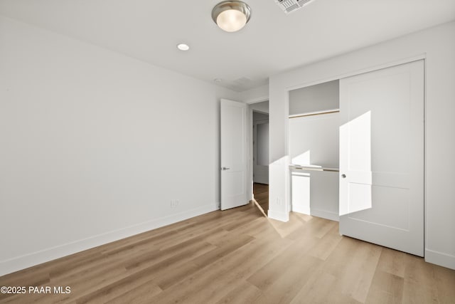 unfurnished bedroom with light wood-type flooring and a closet