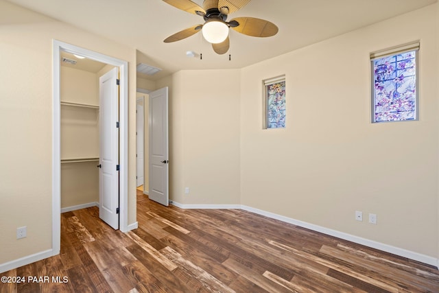 unfurnished bedroom with a closet, a walk in closet, dark hardwood / wood-style floors, and ceiling fan