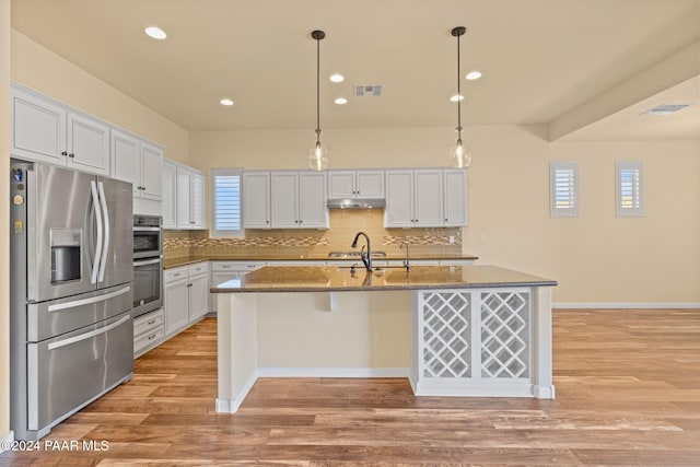 kitchen with light hardwood / wood-style floors, white cabinetry, stainless steel appliances, and an island with sink