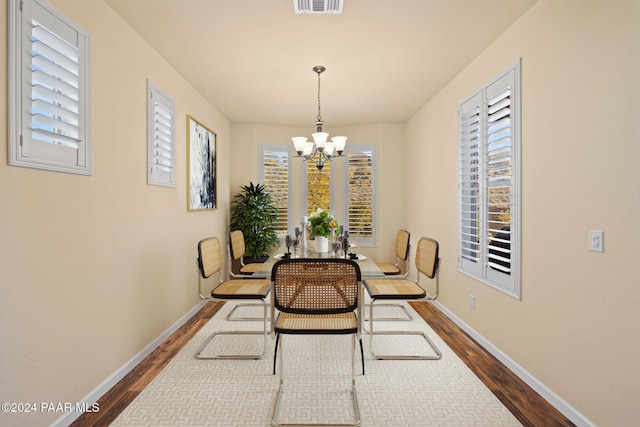 dining room with dark hardwood / wood-style floors and an inviting chandelier