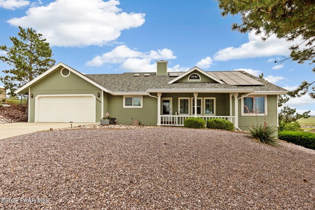 single story home with solar panels, a mountain view, a porch, and a garage