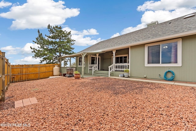 back of property with covered porch, a patio, a shingled roof, and a fenced backyard