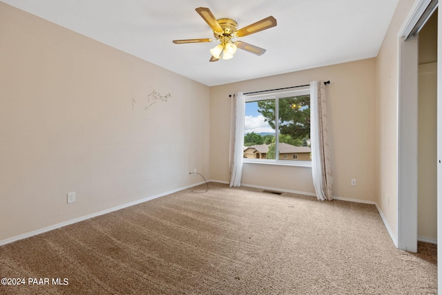 empty room with ceiling fan, baseboards, visible vents, and light carpet