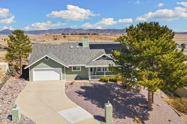 ranch-style home with solar panels, a porch, and a garage