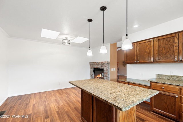 kitchen with a kitchen island, a brick fireplace, a skylight, and wood finished floors