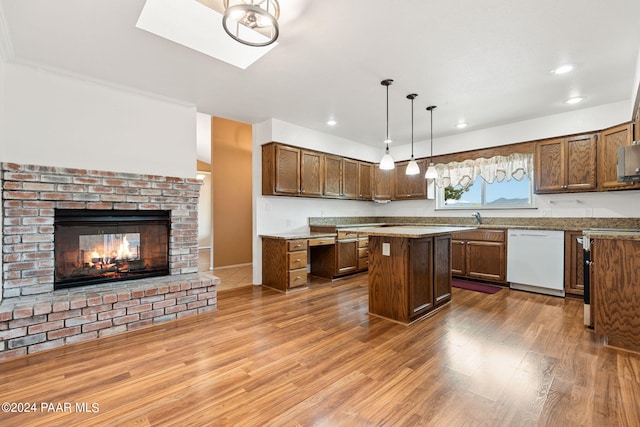 kitchen featuring wood finished floors, a fireplace, white dishwasher, open floor plan, and a center island