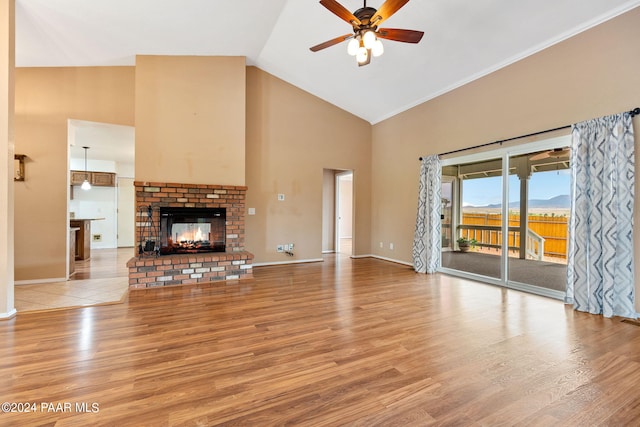 unfurnished living room featuring light wood-type flooring, high vaulted ceiling, ceiling fan, and a fireplace