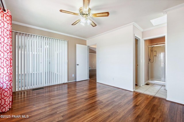 unfurnished bedroom featuring visible vents, wood finished floors, a skylight, and crown molding