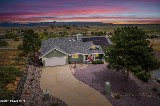 ranch-style house with fence, driveway, a shingled roof, a garage, and a mountain view