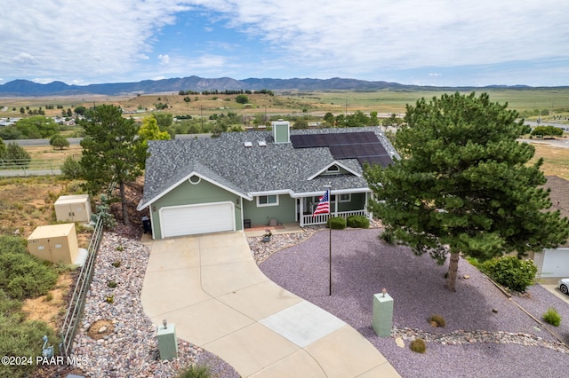 ranch-style home featuring concrete driveway, a garage, a mountain view, and a shingled roof