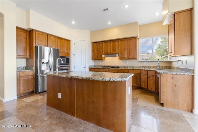5560 W Halcyone Cir, Prescott, AZ 86305 - kitchen featuring light stone counters, stainless steel appliances, visible vents, brown cabinetry, and under cabinet range hood