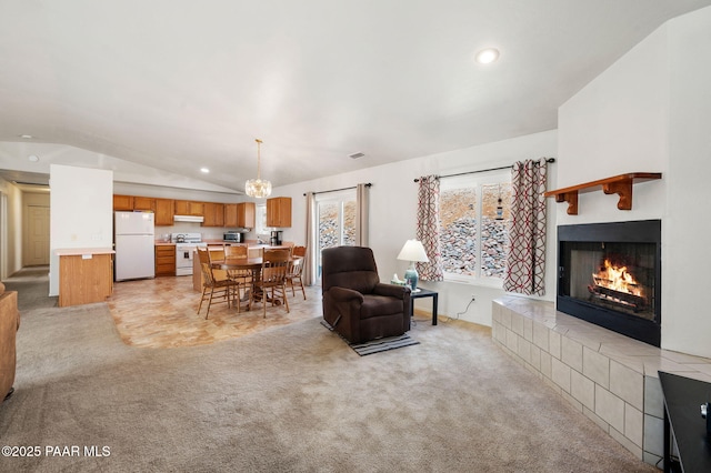 living area featuring recessed lighting, a warm lit fireplace, light colored carpet, and vaulted ceiling