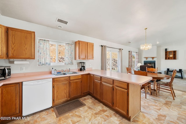 kitchen featuring visible vents, stainless steel microwave, white dishwasher, light countertops, and a sink