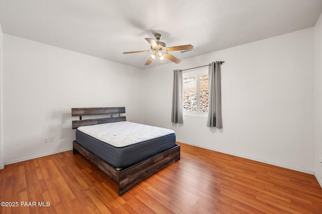 bedroom featuring ceiling fan, baseboards, and wood finished floors